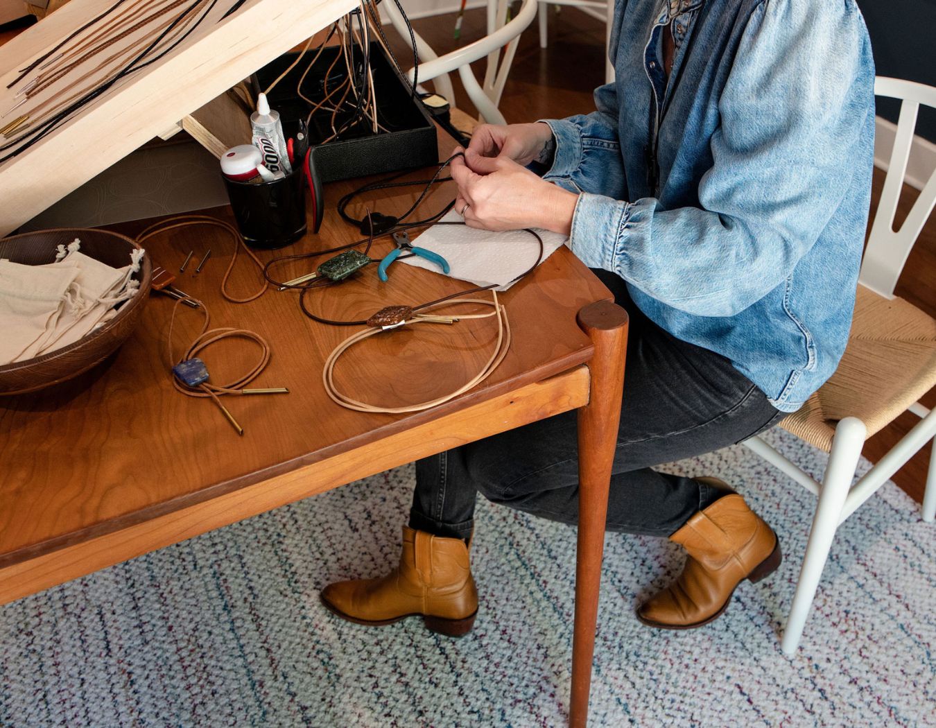 Artisan assembling a custom bolo tie with glass slide and leather cord at Austin Bolo studio