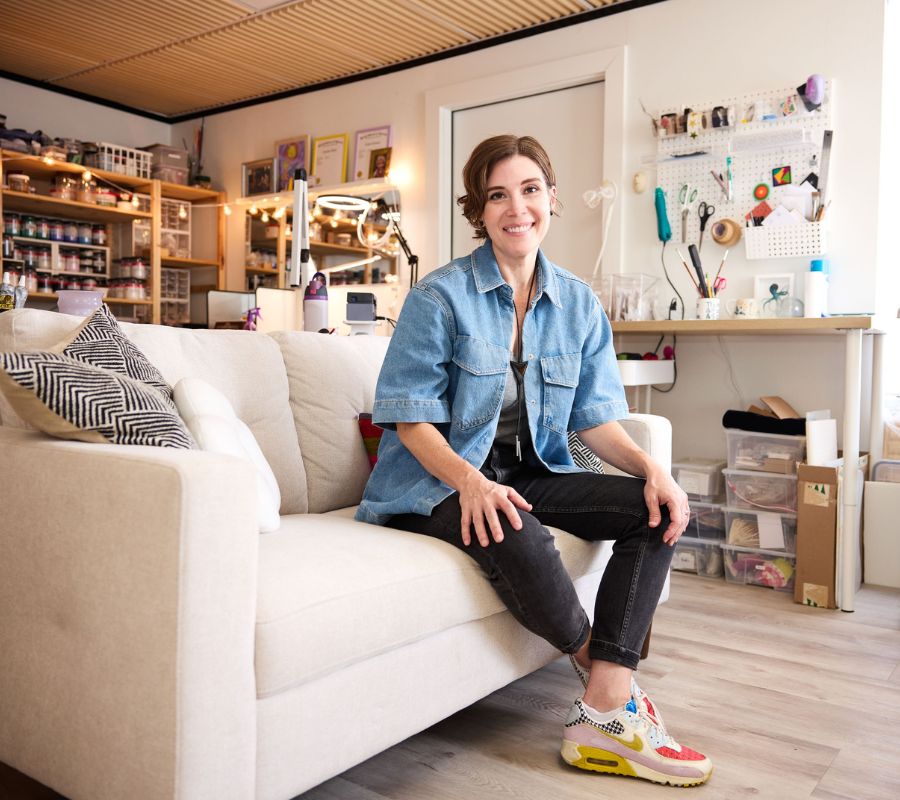 Person sitting on a white couch in a room with shelves and decor.